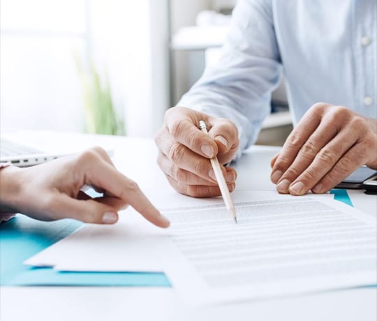 Hands reviewing contract with pencil pointing at document